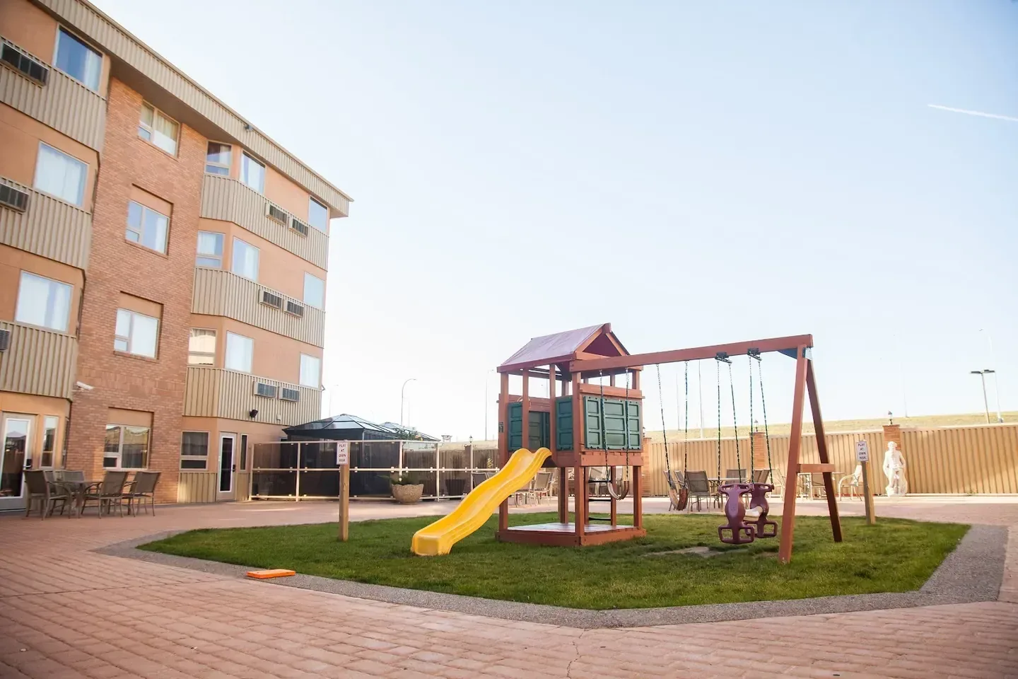 The brick exterior of Medicine Hat Lodge with a small play area in the courtyard